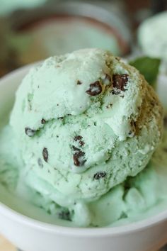 two scoops of mint ice cream in a white bowl on a wooden table top