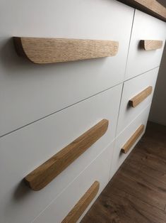 a white cabinet with some wooden handles on the top and bottom drawers in front of it