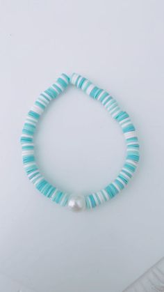 a blue and white beaded bracelet with a pearl on the end, sitting on a table