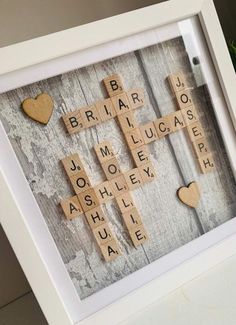 scrabbles are arranged in the shape of hearts on a white frame with a wooden background