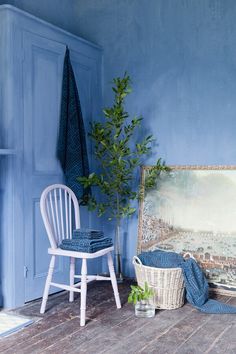 a room with blue walls and a painting on the wall next to a white chair