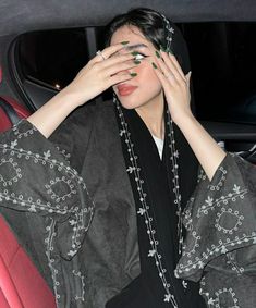 a woman sitting in the back seat of a car holding her hands to her face