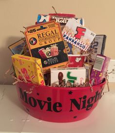 a red bowl filled with lots of different types of movie related items on top of a table