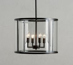 a light fixture hanging from the ceiling with three lights on each side and two candles in between