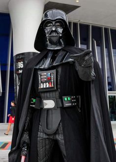 darth vader is standing in front of a building with his hand on his hip