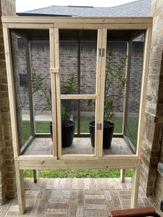 a wooden window sitting on top of a brick wall next to a planter filled with flowers