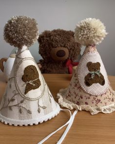 two teddy bears sitting next to each other on top of a wooden table and one is wearing a dress