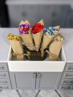 there are many flowers in the paper bags on the counter top, and one is tied with twine