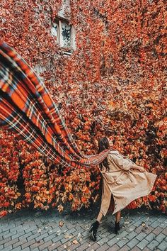 a woman is walking down the street with an orange and black blanket on her back