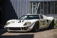 a white race car is parked in front of a building with an open door on the side