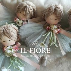 four little dolls with flowers on their heads and tutues, all dressed in different colors