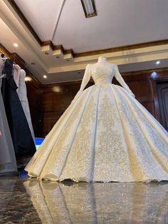 a white wedding dress on display in a room with mannequins behind it