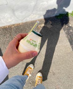 a person holding a bottle of yogurt in their hand with the shadow of someone standing next to them