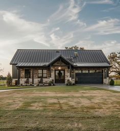 a house with a black metal roof and two car garages on the front lawn