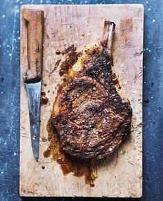 a steak is on a cutting board with a knife and fork next to the meat