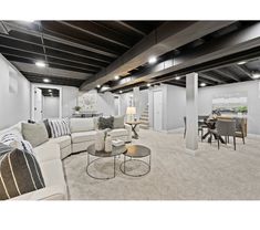 a living room filled with furniture next to a dining room table and chairs on top of carpeted flooring