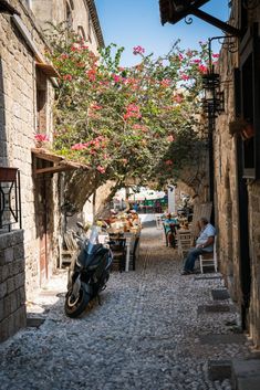 a motorcycle parked on the side of a cobblestone road next to a tree