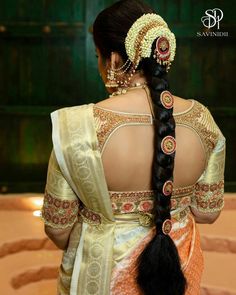 a woman with long black hair wearing a white and gold sari