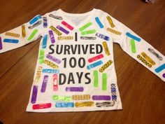 a white shirt that says i survived 100 days on the front and colorful writing on the back