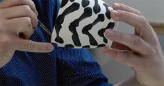 a woman is holding a coffee cup with black and white designs on it