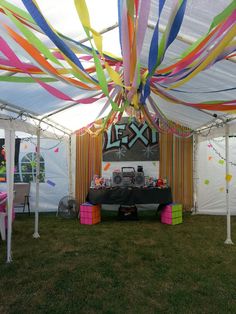 a party tent with colorful streamers hanging from the ceiling and decorations on the walls