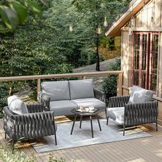 an outdoor living area with wicker furniture on a wooden deck surrounded by greenery