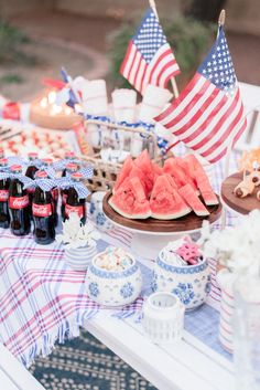 watermelon slices and other foods on a picnic table with american flags in the background