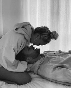 a man and woman laying in bed with each other's heads touching foreheads