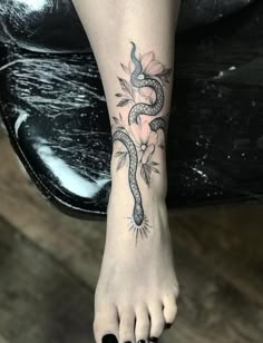 a woman's foot with a snake tattoo on it