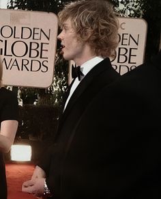 two people in tuxedos are talking to each other at the golden globe awards