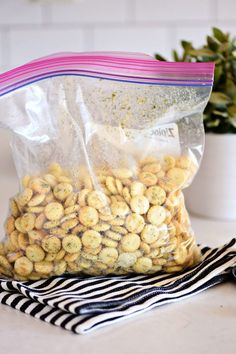 a bag filled with peanuts sitting on top of a table next to a potted plant