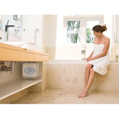 a woman in a bathrobe is sitting on the edge of a bathroom sink