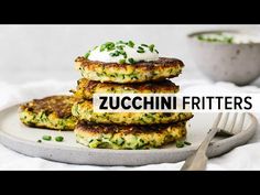 zucchini fritters on a plate with a fork and bowl in the background