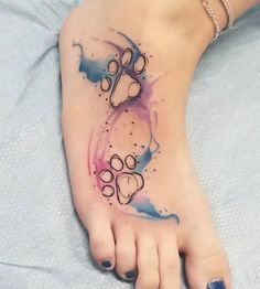 a woman's foot with watercolor tattoos on it