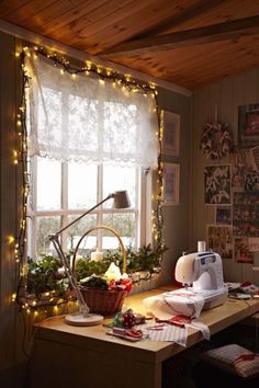 a sewing machine sitting on top of a table next to a window covered in christmas lights