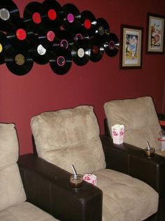 two recliner chairs in front of a red wall with vinyl records hanging on it