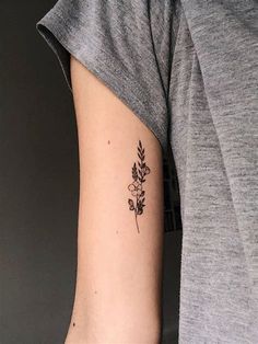 a woman's arm with a small flower tattoo on the left side of her arm