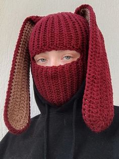 a person wearing a knitted hat with ears on their head and covering his face