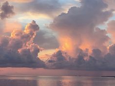 the sky is filled with colorful clouds as the sun sets over the ocean in the distance