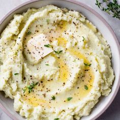 a bowl filled with mashed potatoes on top of a white tablecloth next to a spoon