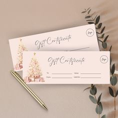 two gift certificates sitting on top of a table next to a pen and plant