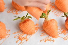 someone is decorating carrots with orange icing on the table and strawberries