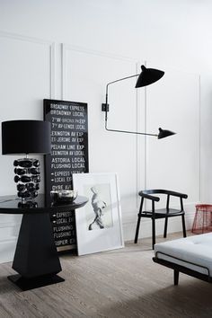 a living room filled with furniture and pictures on the wall next to a lamp that is hanging over a table