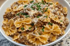 a close up of a bowl of pasta with meat and parmesan cheese on top