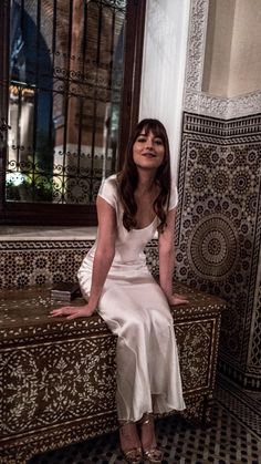 a woman in a white dress sitting on a bench