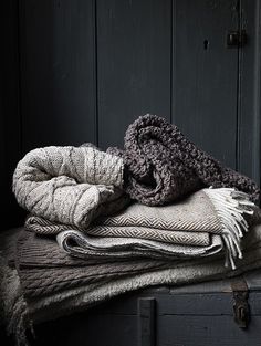 a pile of blankets sitting on top of an old trunk in front of a wooden door