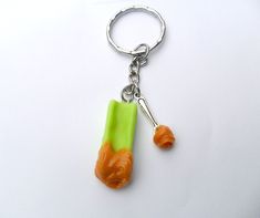 an orange and green object is hanging from a keychain on a white surface