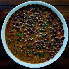 a white bowl filled with beans on top of a wooden table