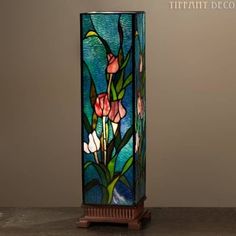 a stained glass vase sitting on top of a wooden table next to a lamp shade