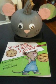 a stuffed mouse and cookie book on a table next to a toy mouse with its mouth open